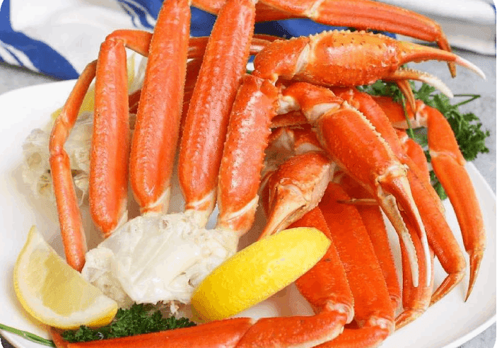 A plate of crab legs and lemon wedges.