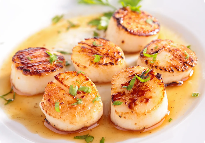 A plate of scallops with sauce on the side.